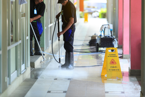 worker pressure washing floor