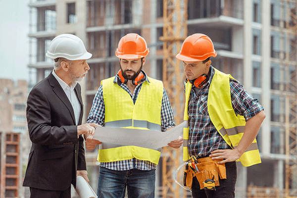 Three men planning construction in hardhats
